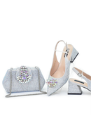 Silver high-heeled shoes and handbag with gemstone embellishments on a white background, Obroi