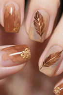 Nails with gold feather and flower designs on a blurred background, Obroi