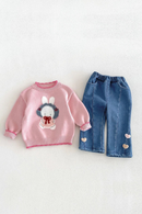 A baby clothing set featuring a pink long-sleeve knit sweater with a bunny graphic and blue denim pants with heart details, laid flat on a light textured background, Obroi