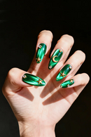 Hand with green nail art featuring stars and moons on a black background, Obroi