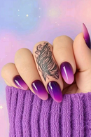 Hand with purple and pink gradient nails and a tattoo on a pastel background, Obroi