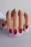 Hand with red nail polish on a light gray background, Obroi
