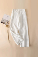 White pants on a beige background with a magazine and dried plant, Obroi