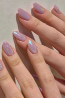 Close-up of a hand with pink glittery nails on a light background, Obroi