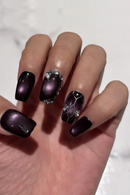 Hand with black and purple nail design on a white background, Obroi