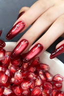 Hand with red nail polish holding a bowl of pomegranate seeds, Obroi