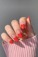 Hand with red heart-shaped nail designs on a gray background, Obroi