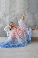 Woman in a colorful tutu sitting on a couch against a gray textured wall, Obroi