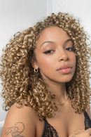 Woman with curly blonde hair wearing a black top against a white background, Obroi