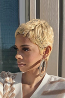 Woman with short blonde hair wearing large hoop earrings, standing in front of a window, Obroi