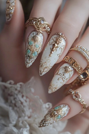 Close-up of a hand with ornate nail art featuring gold and turquoise decorations, Obroi