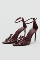 Pair of high-heeled shoes with strappy design on a light gray background, Obroi