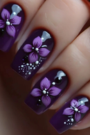 Nails with purple floral design and white accents on a dark background, Obroi