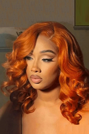 Woman with vibrant orange hair styled in waves, wearing a black top, Obroi