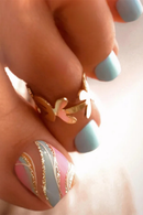 Close-up of a hand with blue nail polish wearing a gold ring on a light background, Obroi