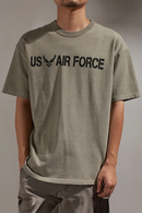 Person wearing a green 'US Air Force' t-shirt against a gray background, Obroi