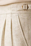 Close-up of a textured beige fabric with a button detail, Obroi