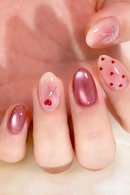 Close-up of a hand with pink and red nail art on a blurred background, Obroi