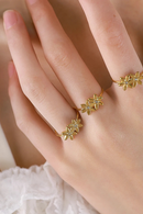 Gold floral rings on a hand with a soft background, Obroi