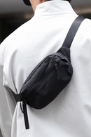 Person wearing a black waist bag on a blurred background, Obroi