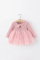 A pink long-sleeve baby dress with a ribbed knit bodice, white lace Peter Pan collar, and a layered tulle tutu skirt, hanging on a wooden hanger against a plain white background, Obroi