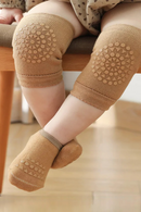 Baby wearing brown knee pads and socks on a wooden floor, Obroi