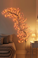 Decorative branch with lights against a wall in a cozy room, Obroi