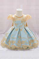 Light blue dress with gold embroidery on a mannequin against a white tiled wall, Obroi