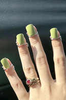Hand with green nail polish and multiple rings on a dark background, Obroi