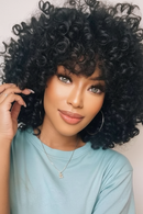 Woman with voluminous curly hair wearing a light blue shirt, Obroi