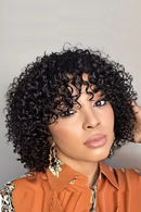Woman with styled hair wearing an orange top against a neutral background, Obroi