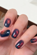 Hand with dark blue and red nail polish on a neutral background, Obroi