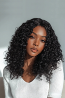 Woman with voluminous curly black hair wearing a light gray sweater against a neutral background, Obroi