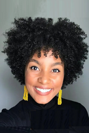 Woman with curly hair wearing yellow earrings against a gray background, Obroi