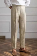 Person wearing beige pants and a white shirt against a white wall, Obroi