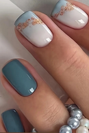 Close-up of a hand with blue and white nails with gold glitter accents, Obroi